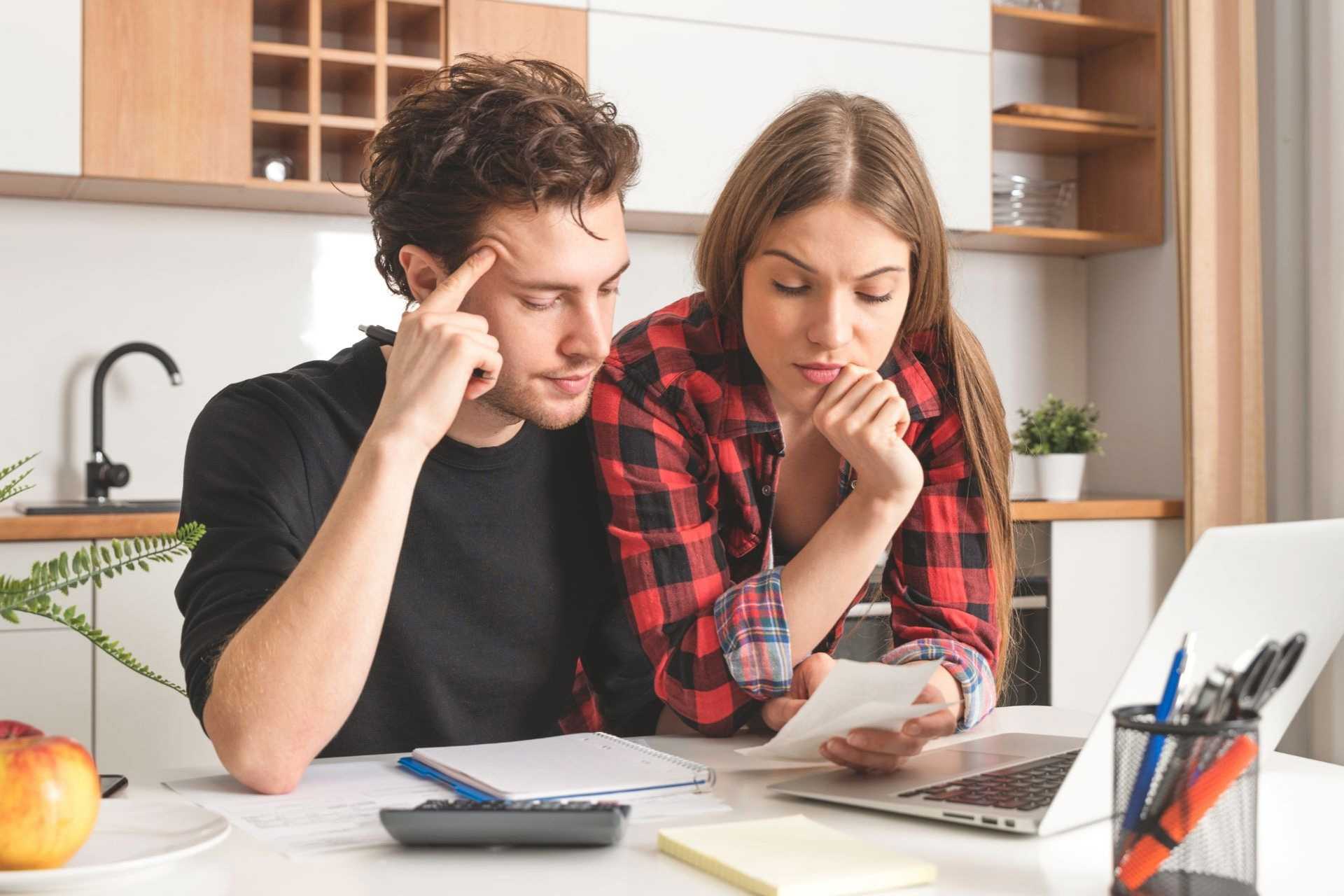 A couple studying a bill with a laptop and calculator 