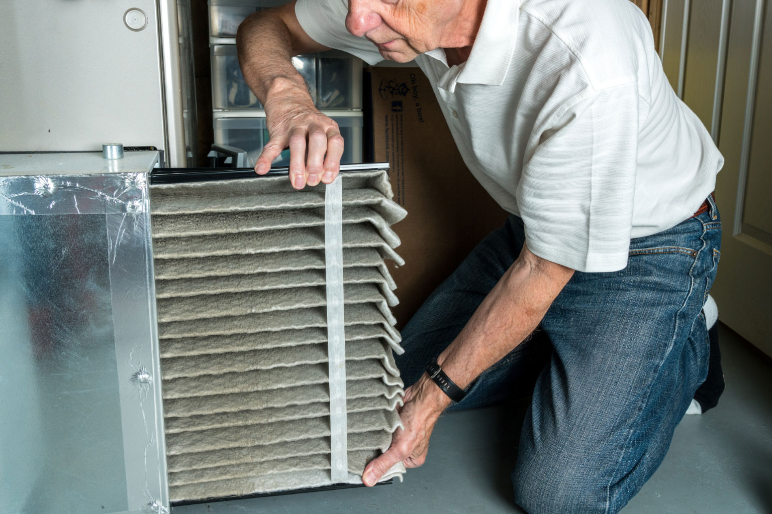 A Man Removing The Air Filter From A Furnace - LG Home Comfort
