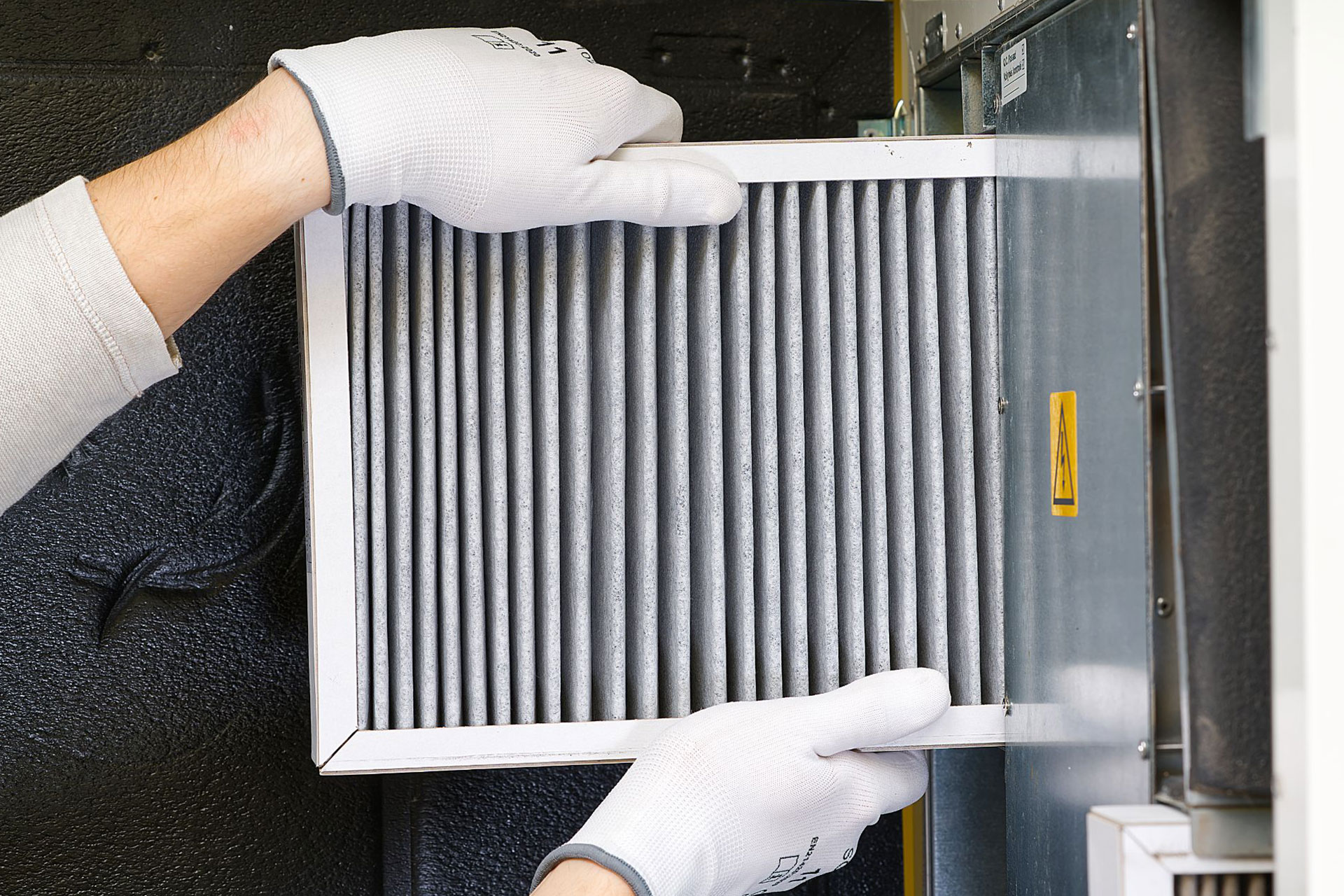 A pair of hands inserting a furnace filter for allergies