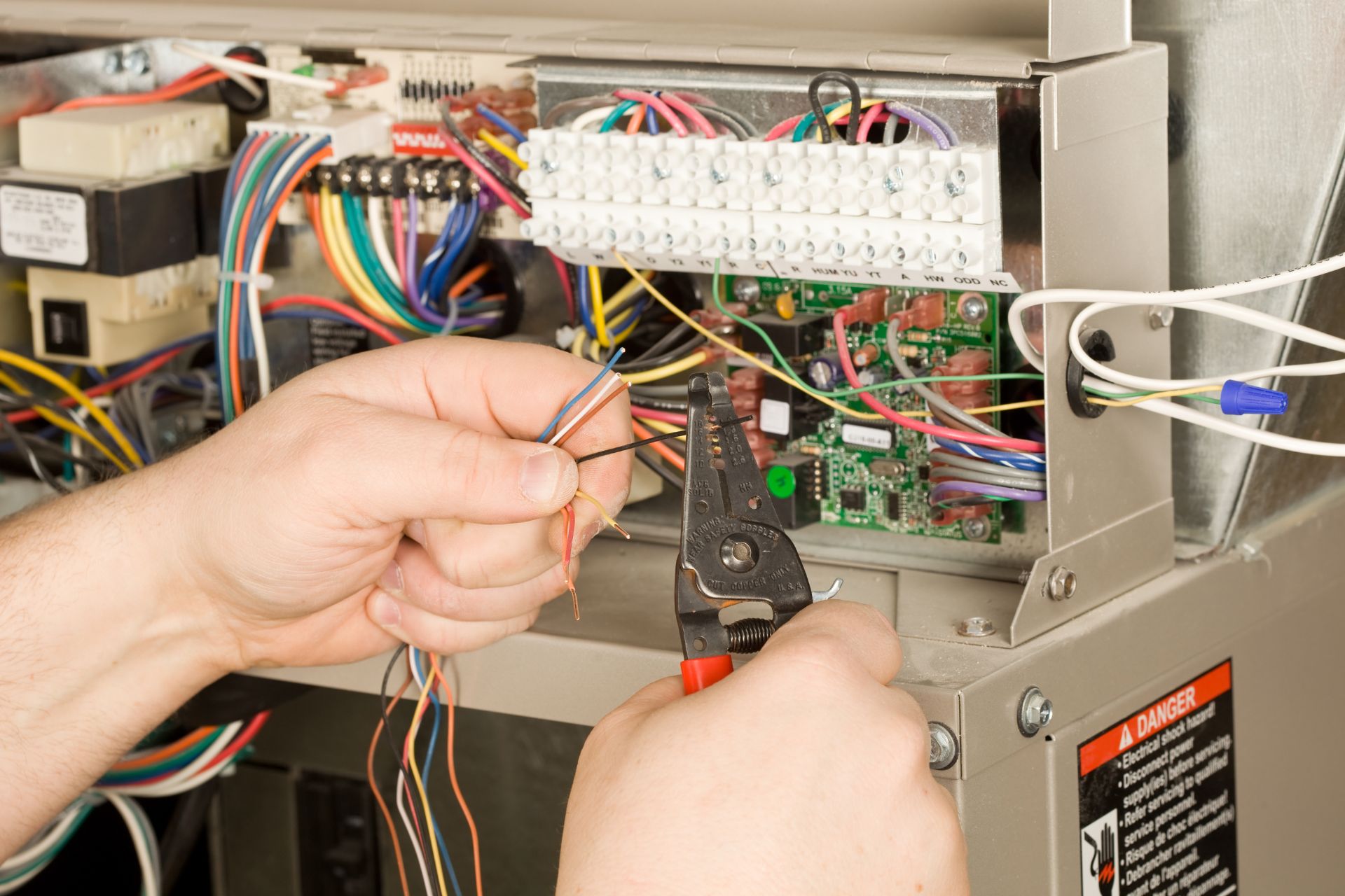 An HVAC technician fixing a furnace’s electrical wiring