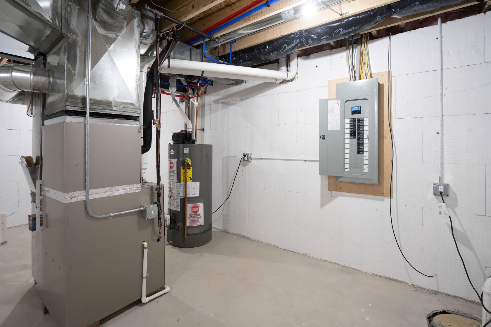 View of a basement updated with new furnace, hot water tank, and electrical panel.