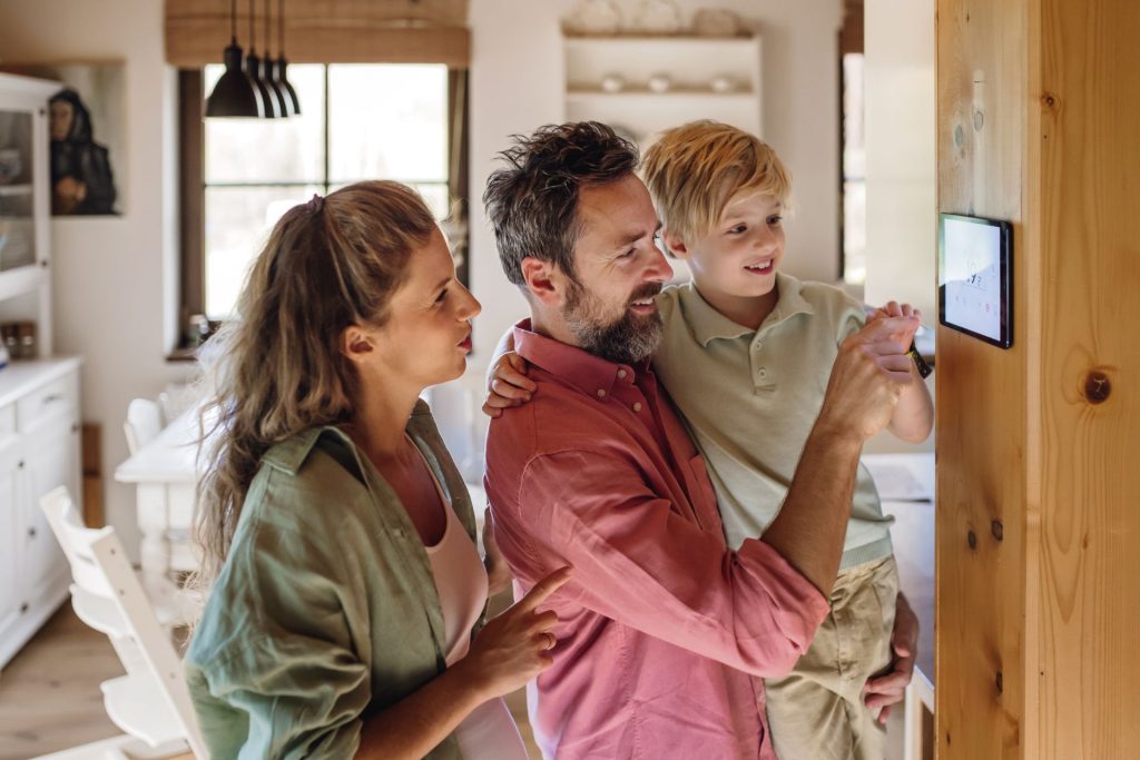 A family of three adjusting the thermostat