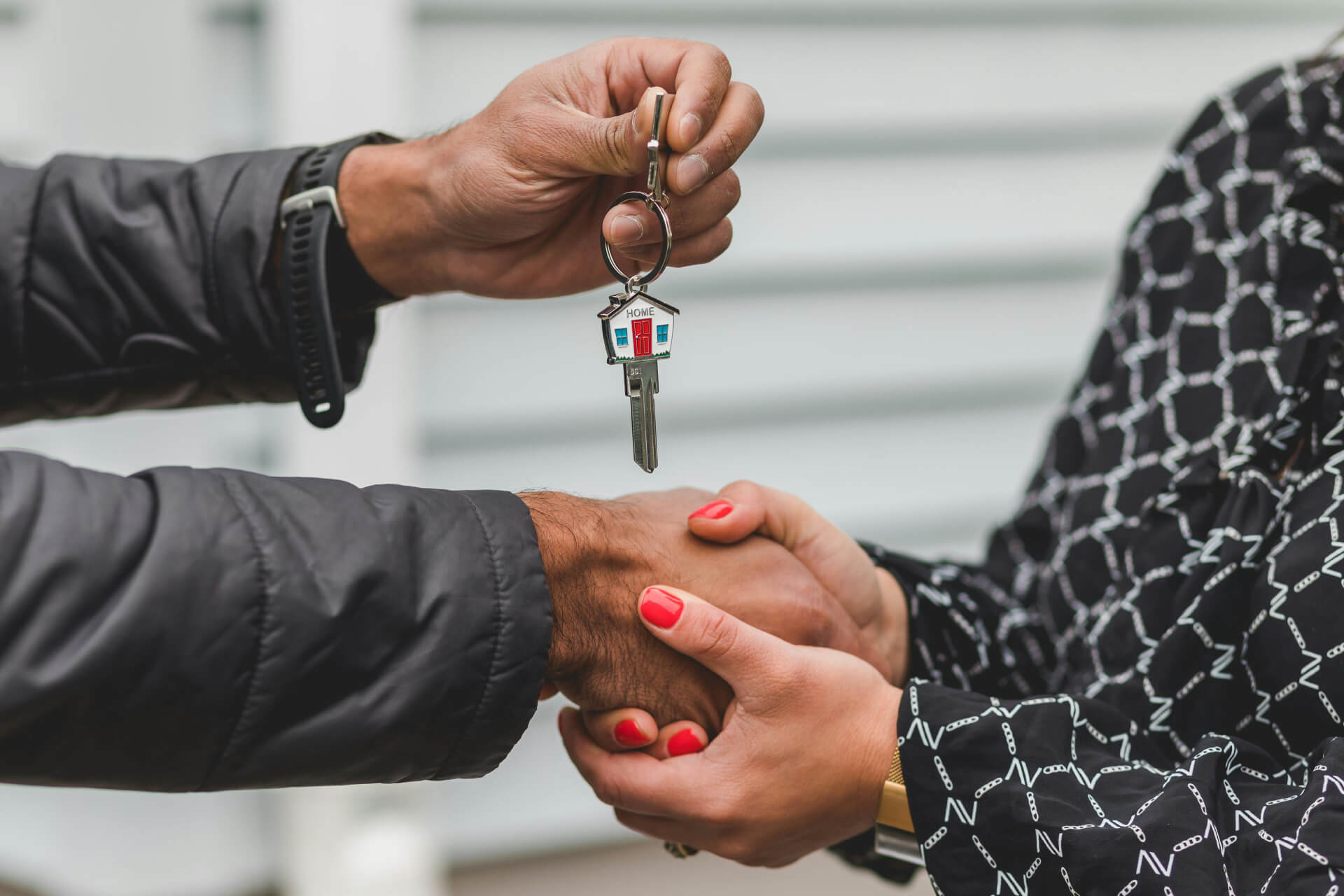 Two people shaking hands and exchanging a set of house keys