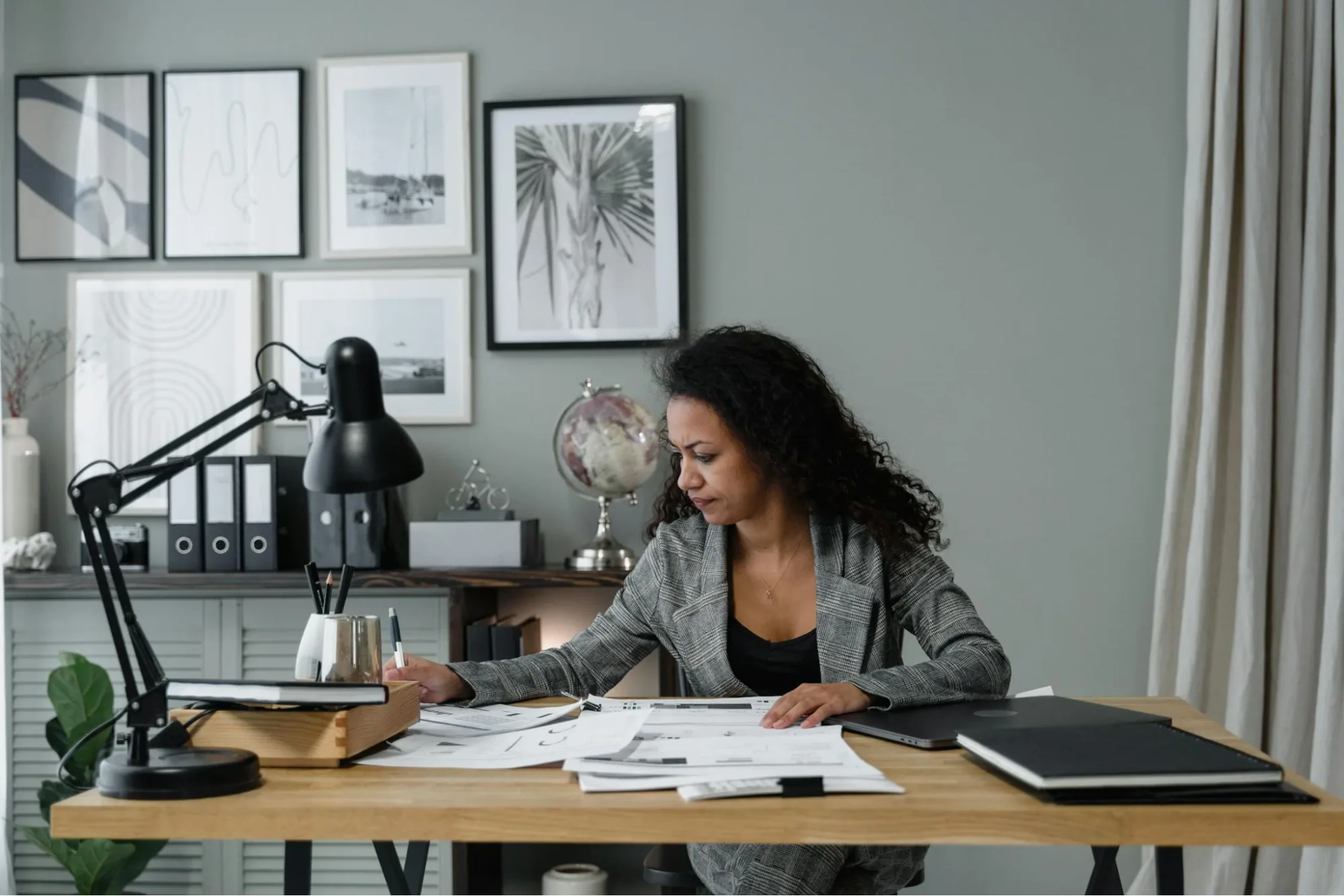 A woman sitting on a chair, focusing on the pile of bills scattered on the table before her.