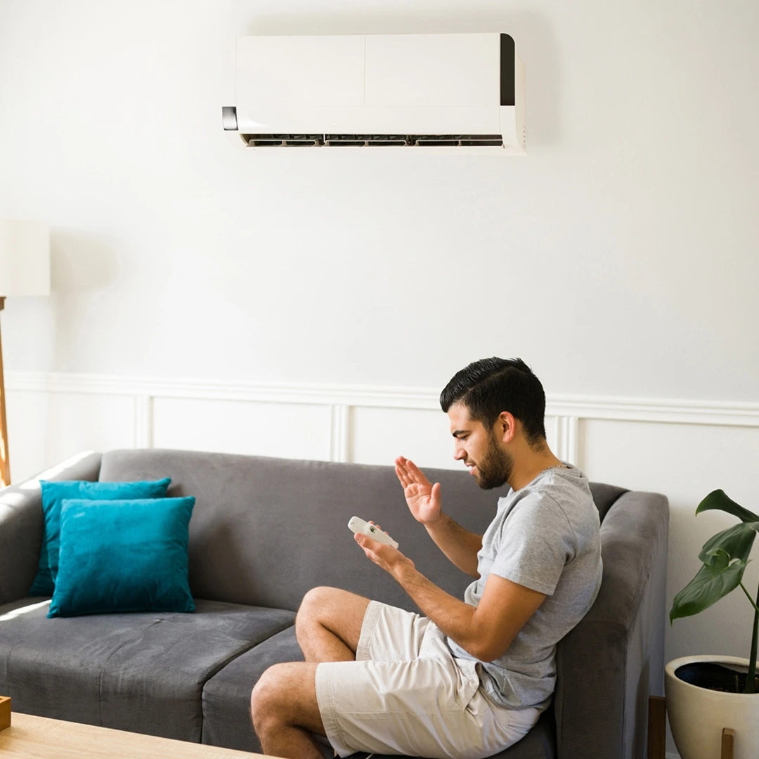 Young man checking AC remote, looking frustrated