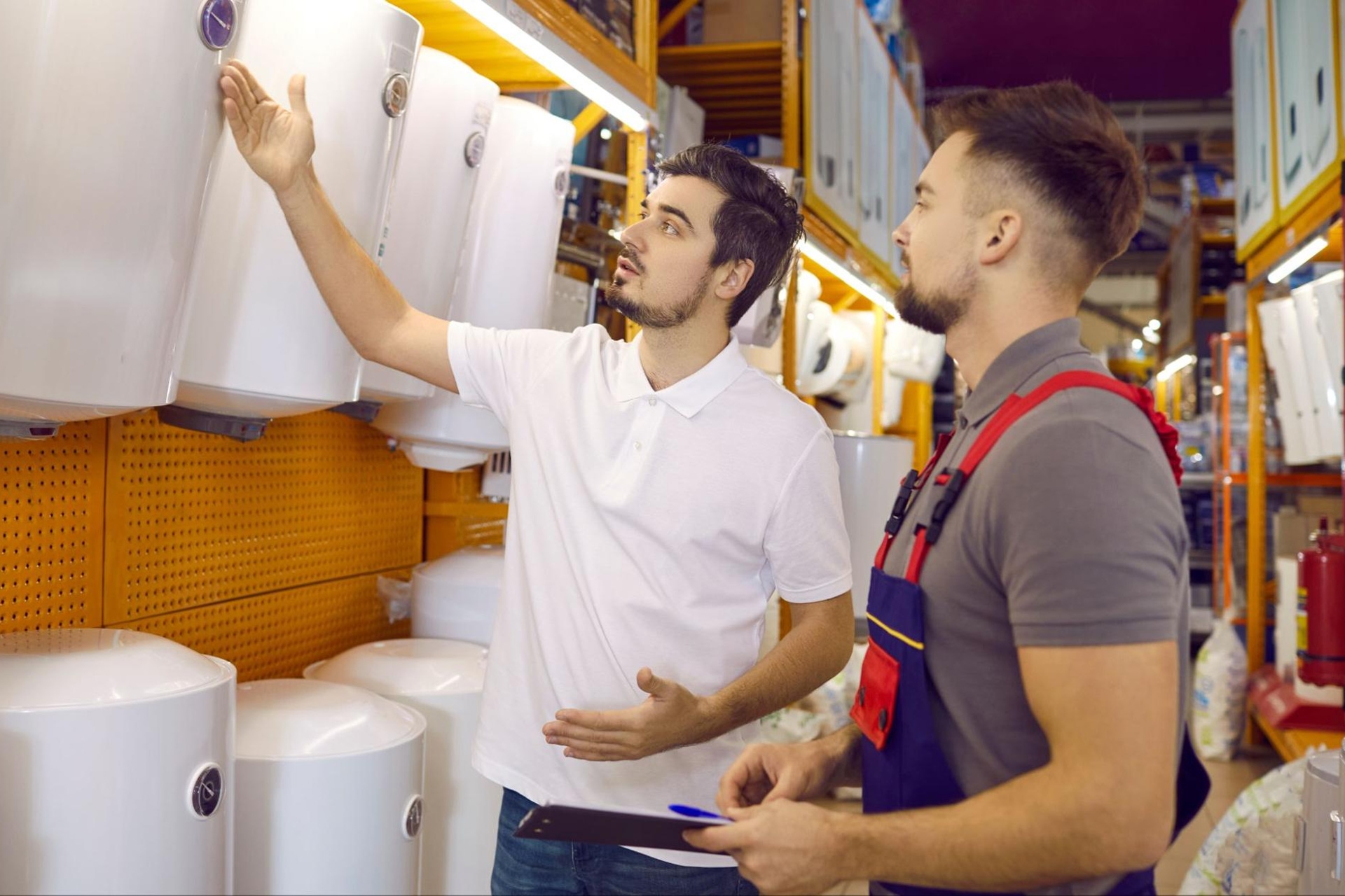 Young man choosing a new heating boiler, assisted by a store employee
