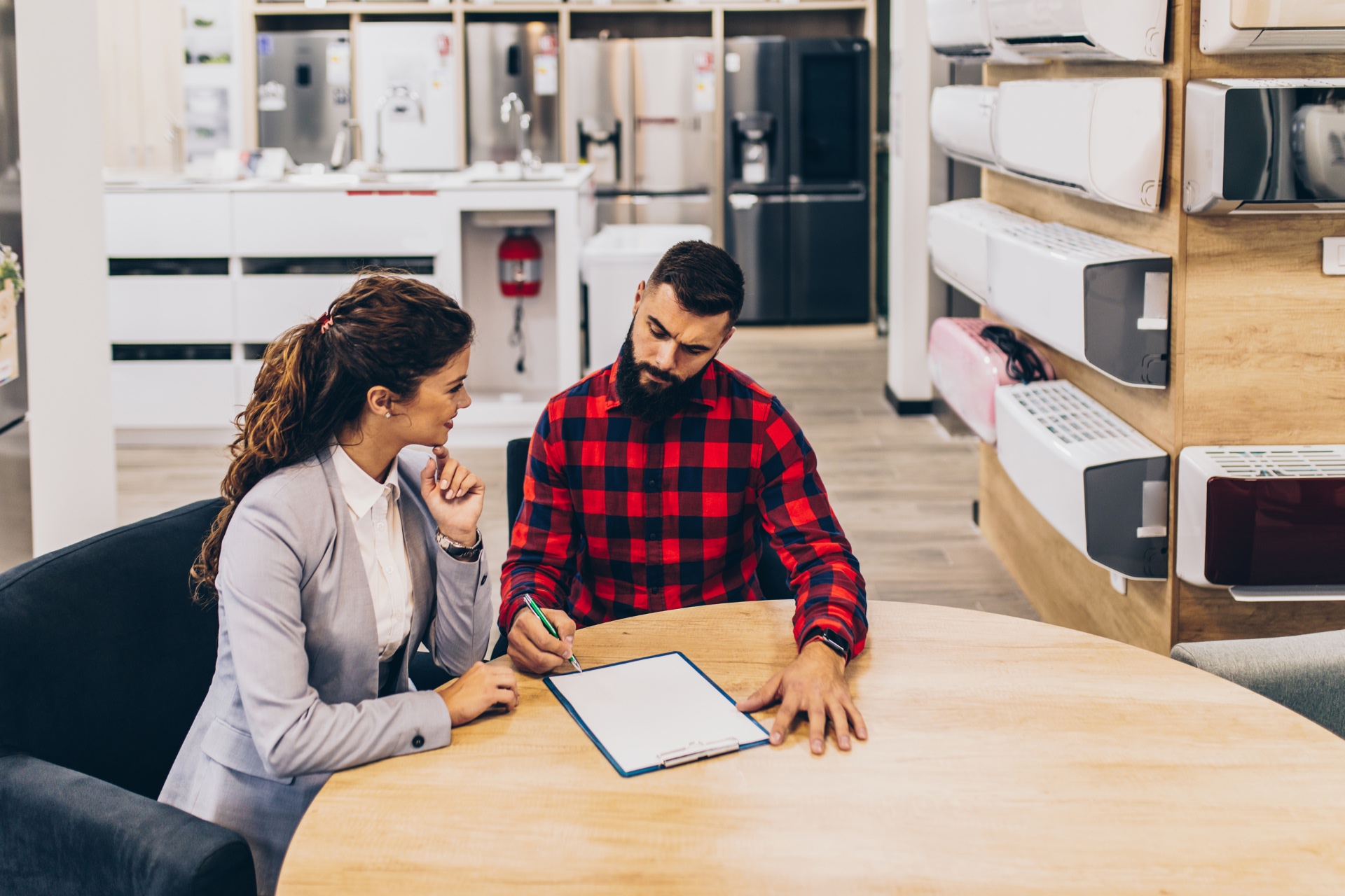 Young man signing a financing contract at an air conditioner store