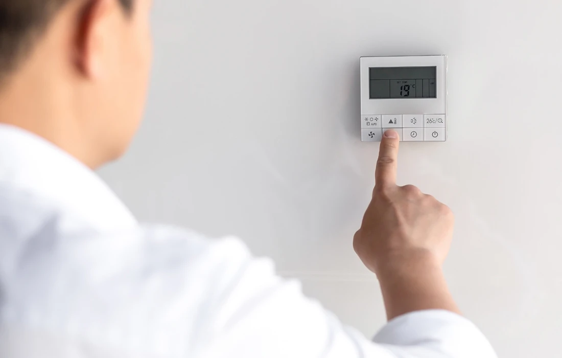 A man lowering the temperature on a thermostat