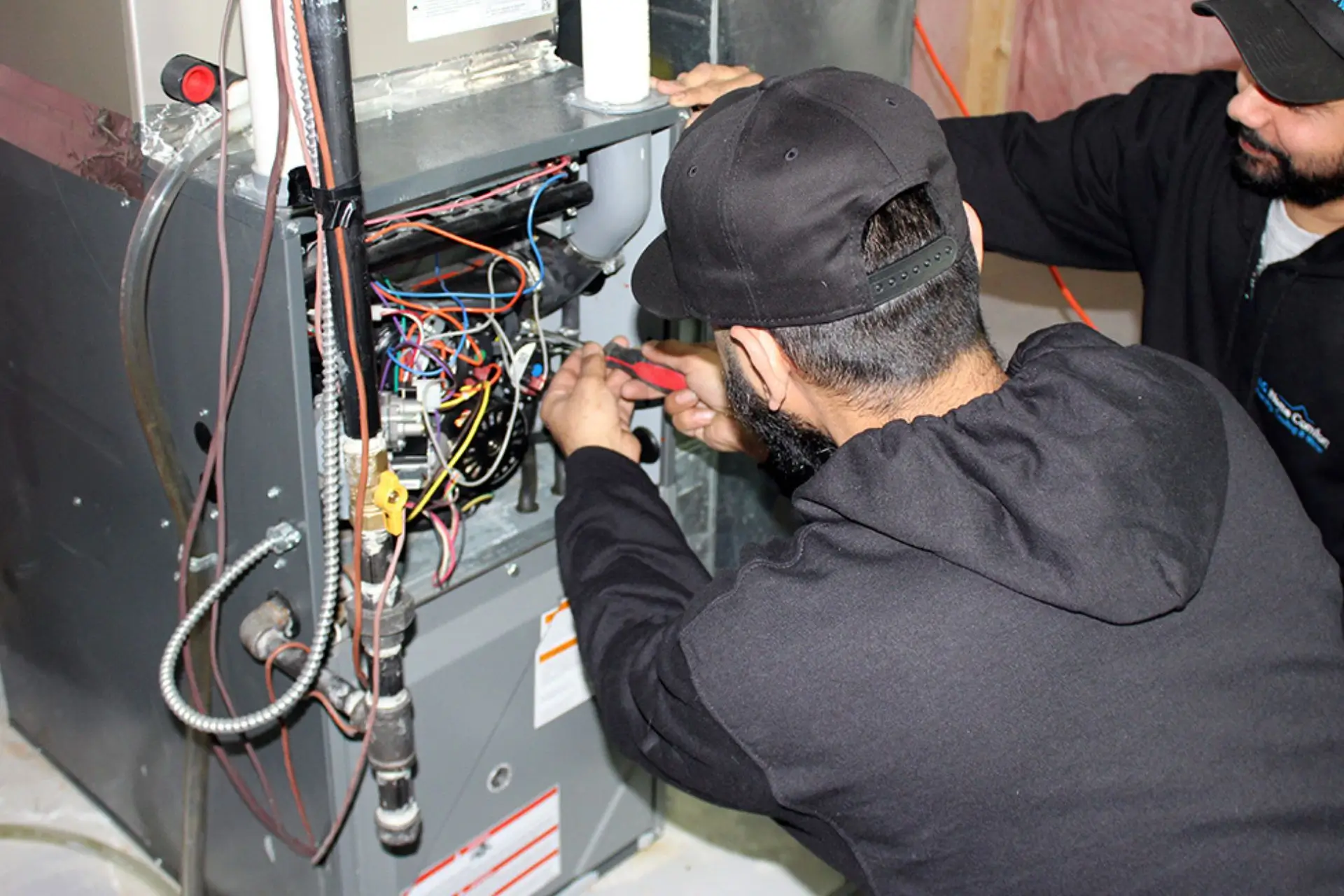 Technicians working on a water heater in a basement