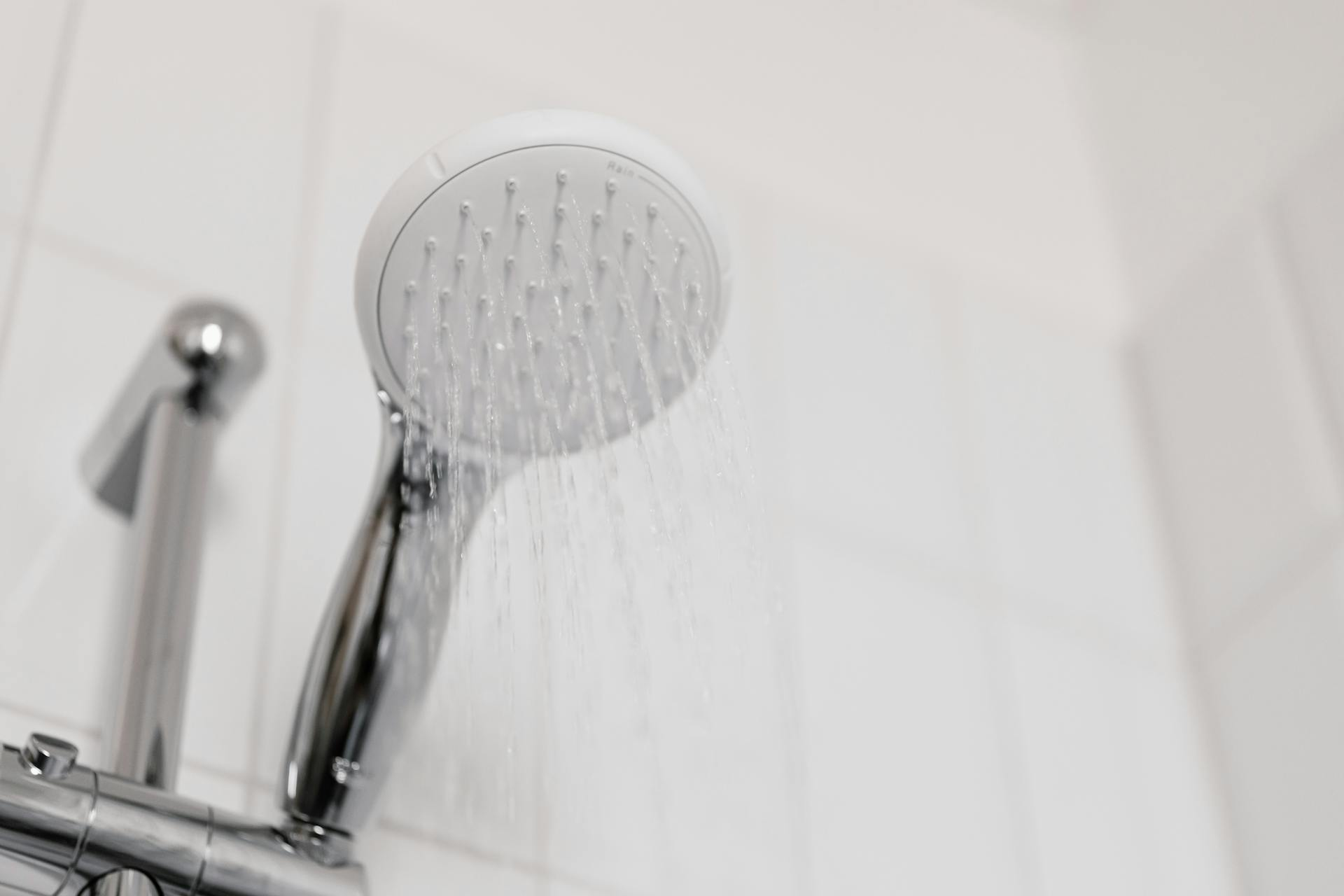A running shower head in a white bathroom