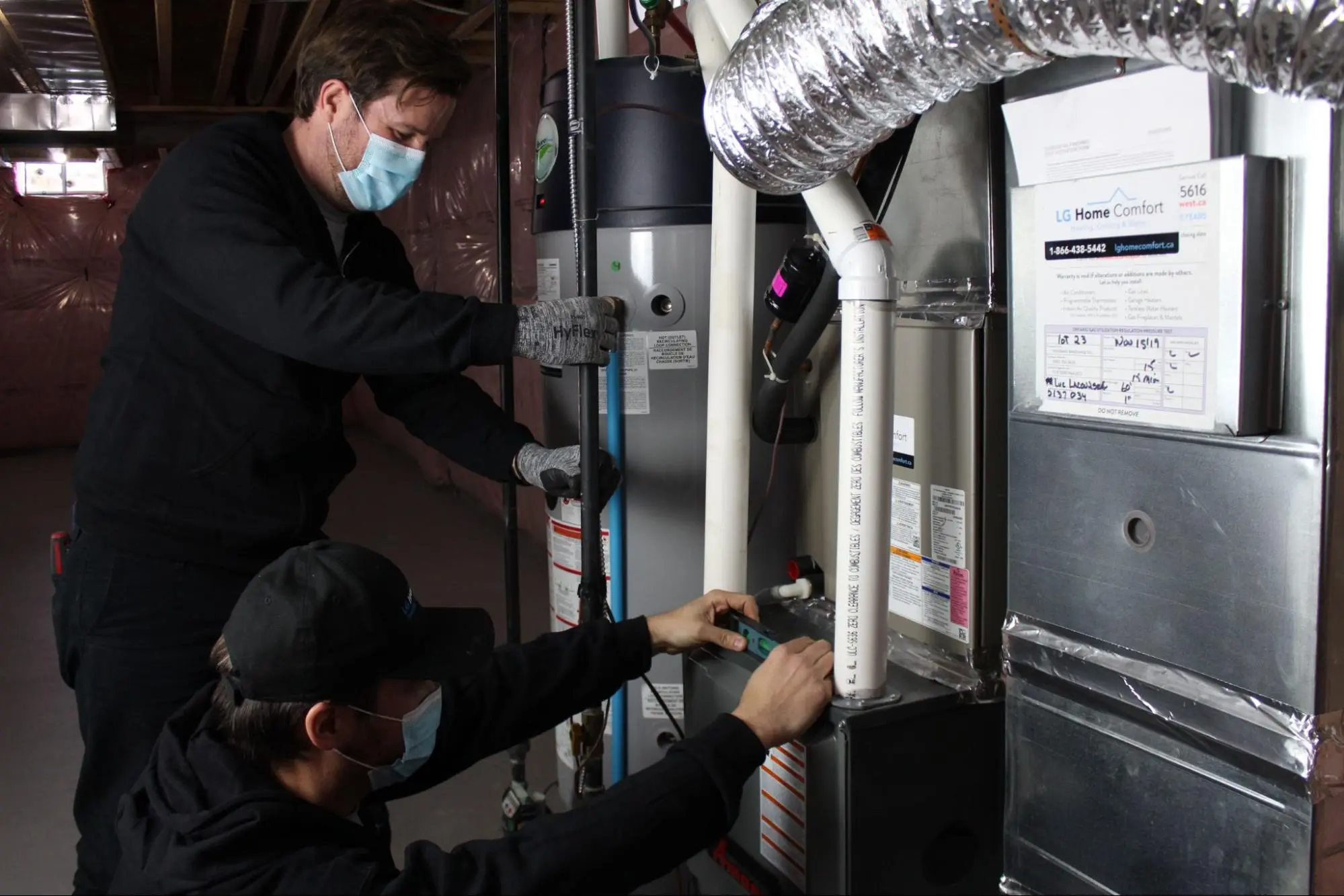 Two technicians wearing masks fixing HVAC system 